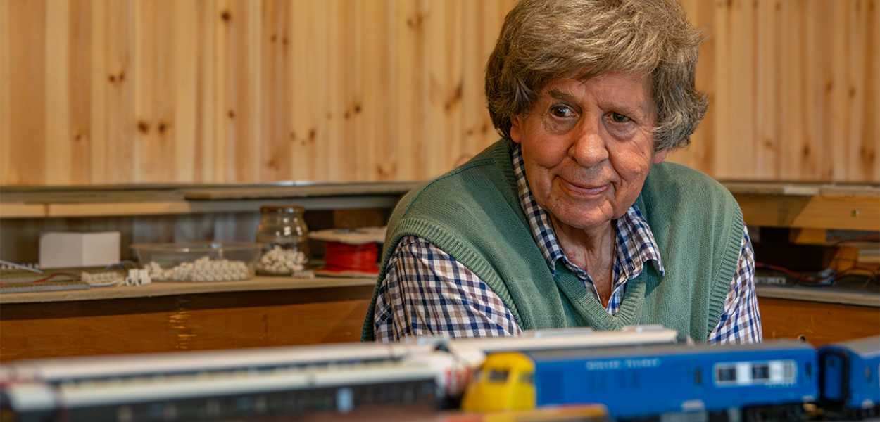 Colin sitting next to his model rail as the train goes past.