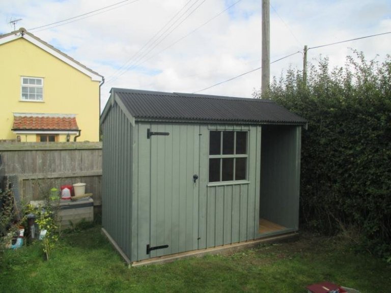 A traditional garden shed from national trust range. National Trust garden shed with corrugated roof, georgian window and vertically-sawn, rustic-cut cladding painted in terrace green. 
