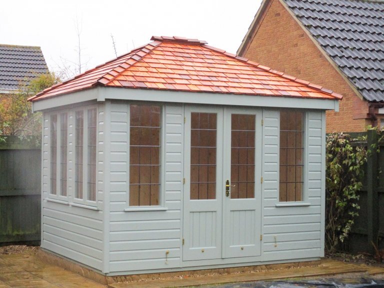 2.4 x 3.0m Cley Summerhouse with cedar shingle tiles on the roof and painted in Exterior Sage