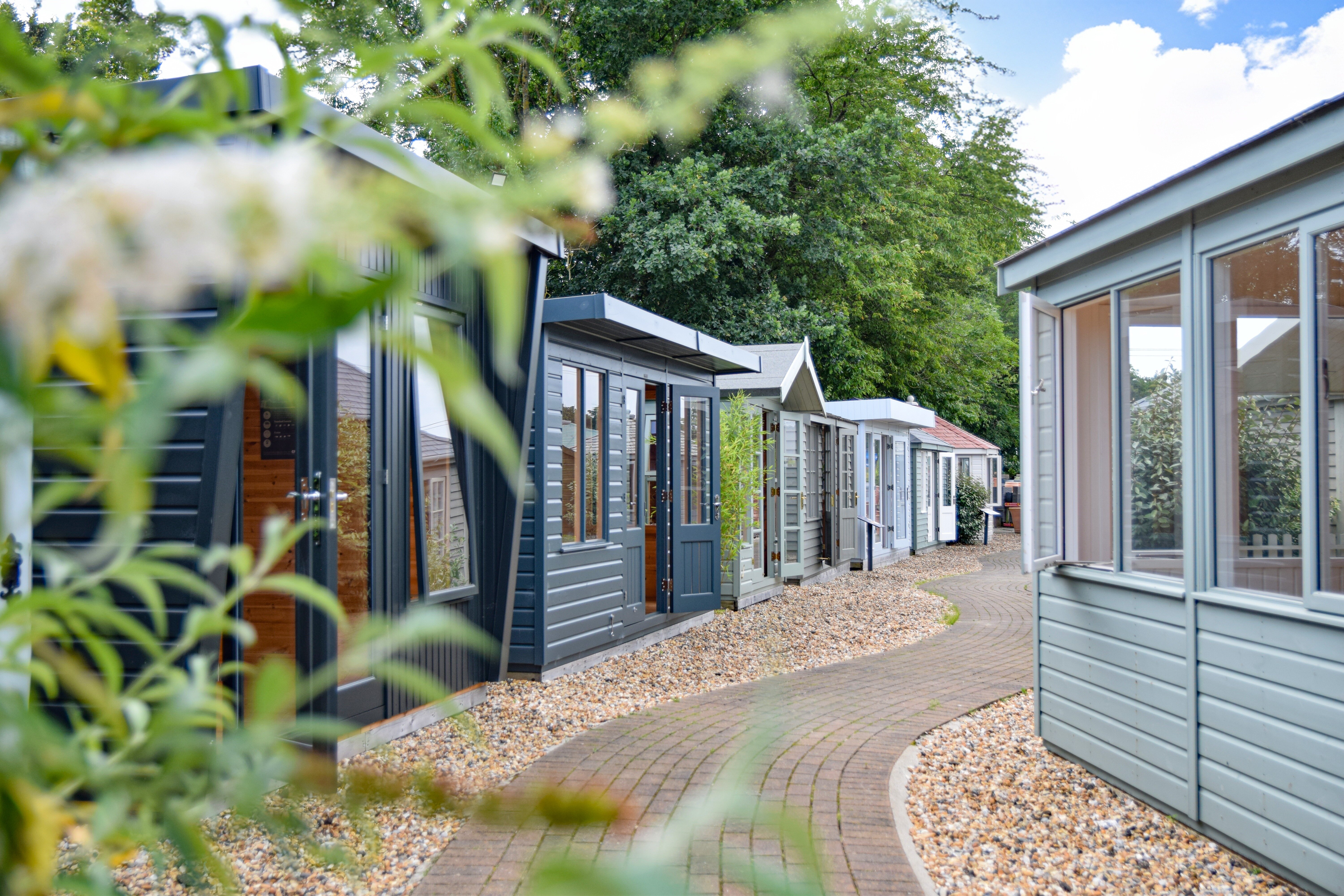 Looking down a winding path at a show centre surrounded by garden studios and summerhouses