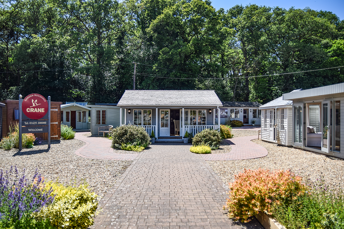 Newbury show centre, where a garden room with veranda sits centrally on a paved area, with other garden rooms, summerhouses and studios visible around it.